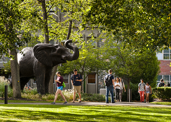 Students of Tufts University are spotted walking to class near the notable 'Jumbo' statue.