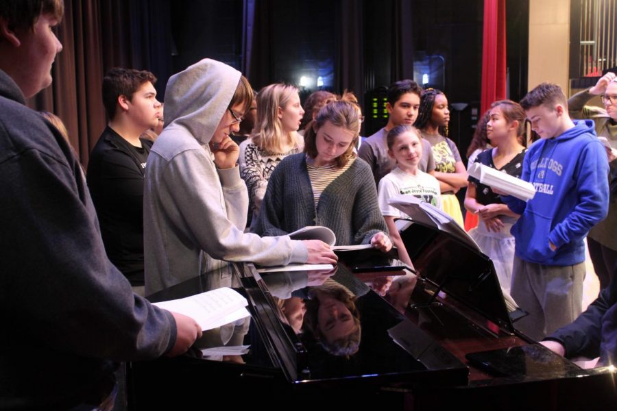 The cast gathers around the piano during a recent rehearsal