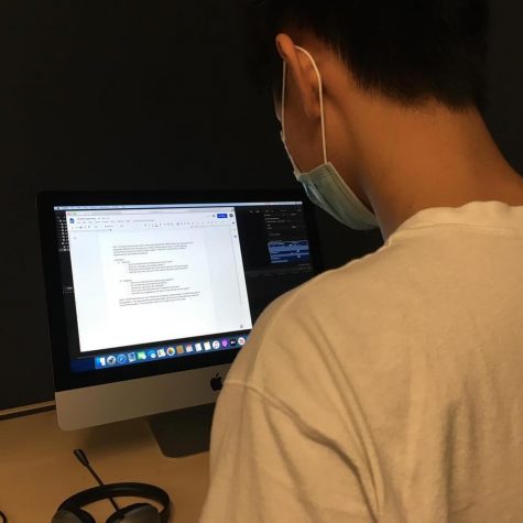 Vincent Tran works on his editing computer with his mask on