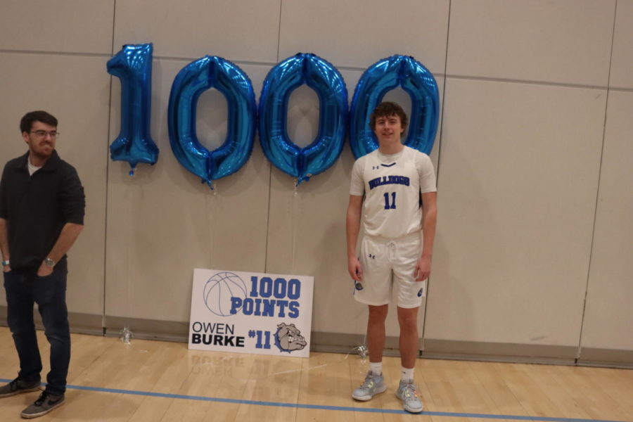 Owen Burke standing next to a custom display to celebrate his 1,000th point in his basketball career