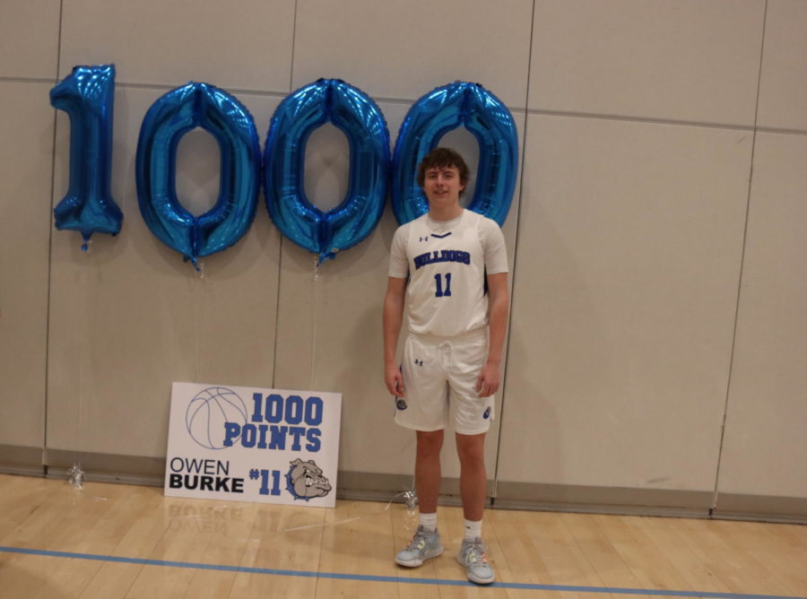 Owen Burke standing next to a personal display dedicated to his 1,000th point